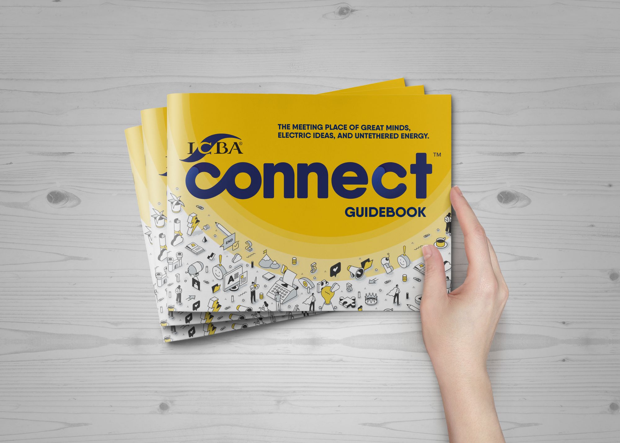 Stacked copies of the ICBA Connect guidebook, one held in a hand